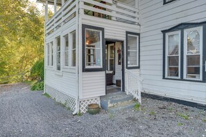 Une maison à deux étages avec un porche, une porte d’entrée et une petite marche menant à l’entrée.