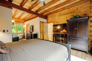 A bedroom with a bed, a wooden ceiling, a television, a cabinet, and a bathroom with a bathtub and sink. - Game Room, Hot Tub! Retreat 3 Mi to Holiday Valley (Ellicottville)