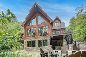 A two-story log cabin with a stone foundation, large windows, and a balcony. - Game Room, Hot Tub! Retreat 3 Mi to Holiday Valley (Ellicottville)