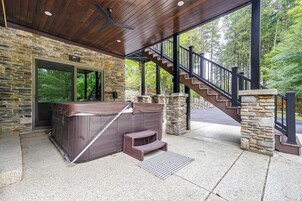 Un área de hidromasaje con pared de piedra, terraza de madera y escalera que lleva a un nivel superior.