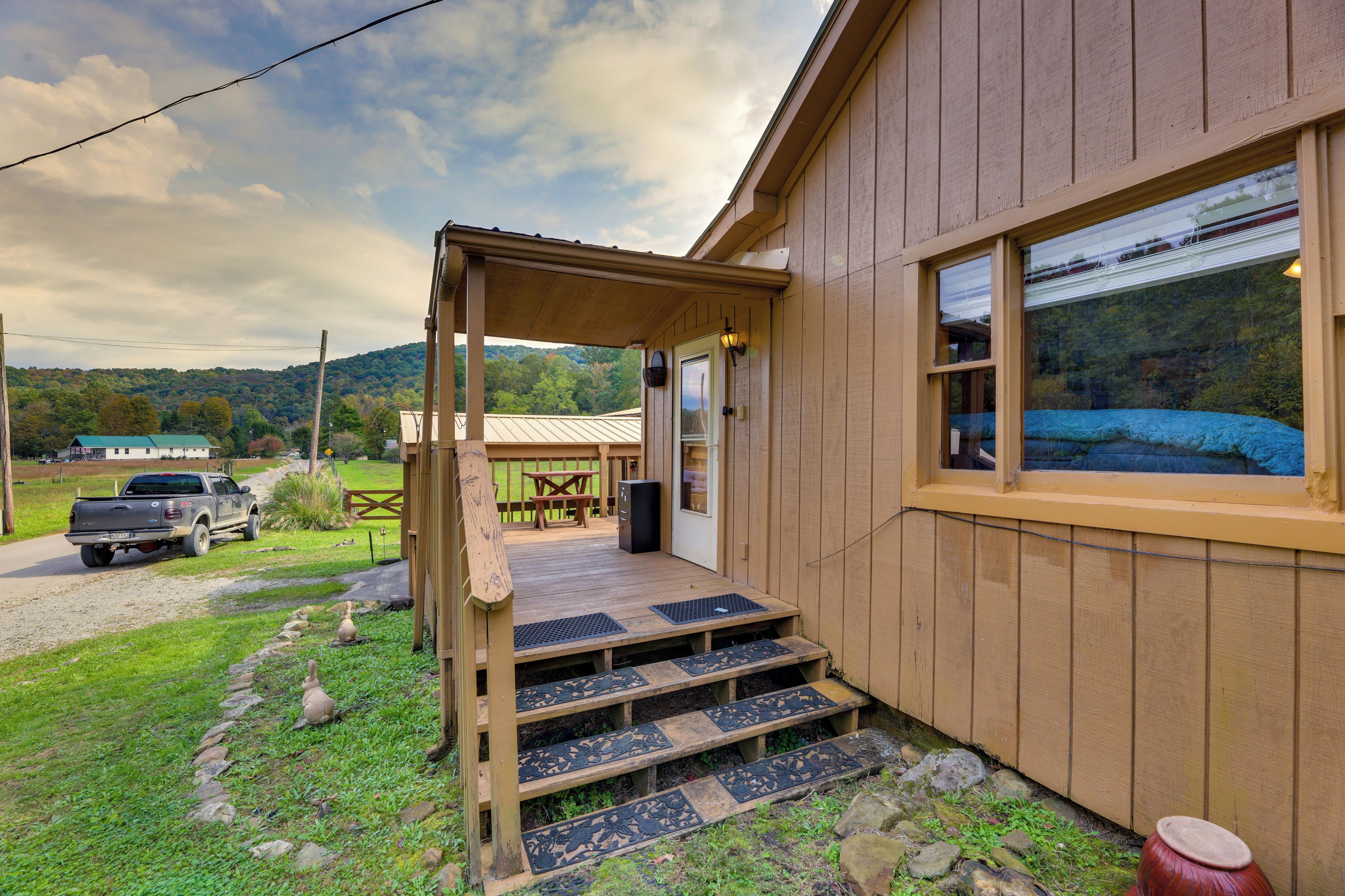 A wooden cabin with a porch, outdoor seating, and a view of the surrounding landscape.
