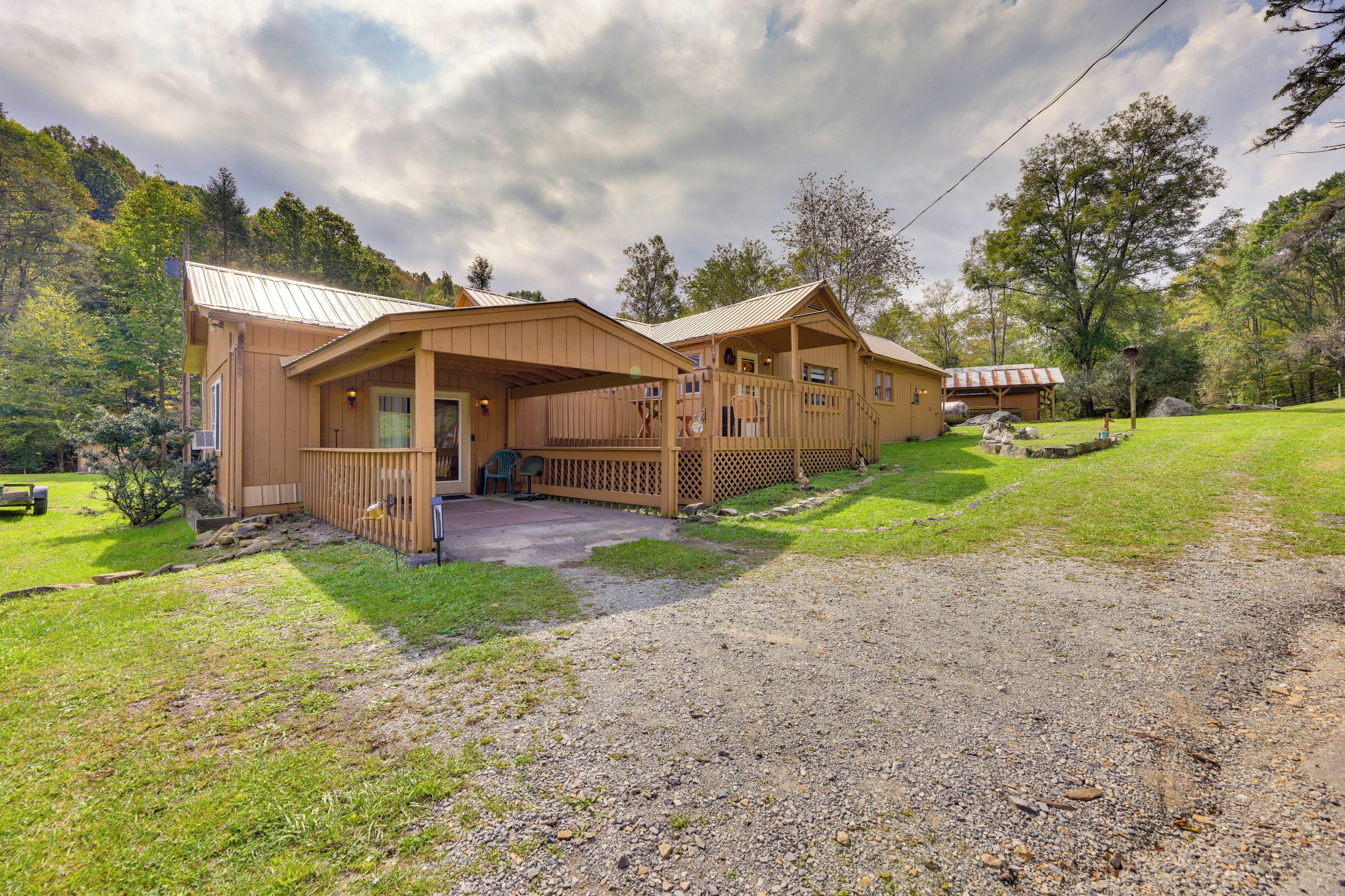 A two-story log cabin with a porch and a covered outdoor seating area.