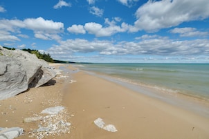 A beach with clear skies, calm waters, and rocky terrain.