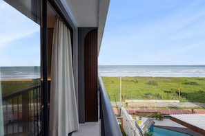 Un balcón con vista al océano, una piscina y un jardín.