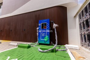 Una estación de carga para vehículos eléctricos VAPT con un código QR, una pantalla digital y un espacio verde para estacionar.