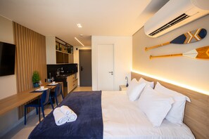 Ein Hotelzimmer mit Bett, Schreibtisch, Stuhl, Fernseher und einem an der Wand befestigten Surfbrett.