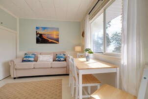 A cozy room with a beige sofa, a wooden table, and a large window with curtains.