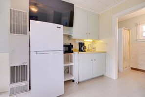 Eine kleine Küche mit einem weißen Kühlschrank, einer Kaffeemaschine und einer Mikrowelle.