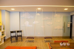 A room with a wooden floor, a reception desk, a wall with cloud patterns, and a door labeled 'BRINQUEDOTECA'. - One Way #203 - Tambau Beach by Carpediem (João Pessoa)