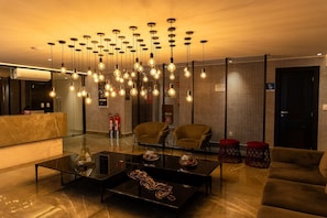 A modern living room with a glass coffee table, two armchairs, a sofa, and a unique ceiling light fixture. - One Way #203 - Tambau Beach by Carpediem (João Pessoa)