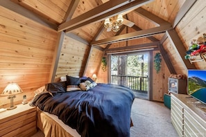 Ein gemütliches Schlafzimmer mit Bett, Nachttisch, Lampe und Fernseher.