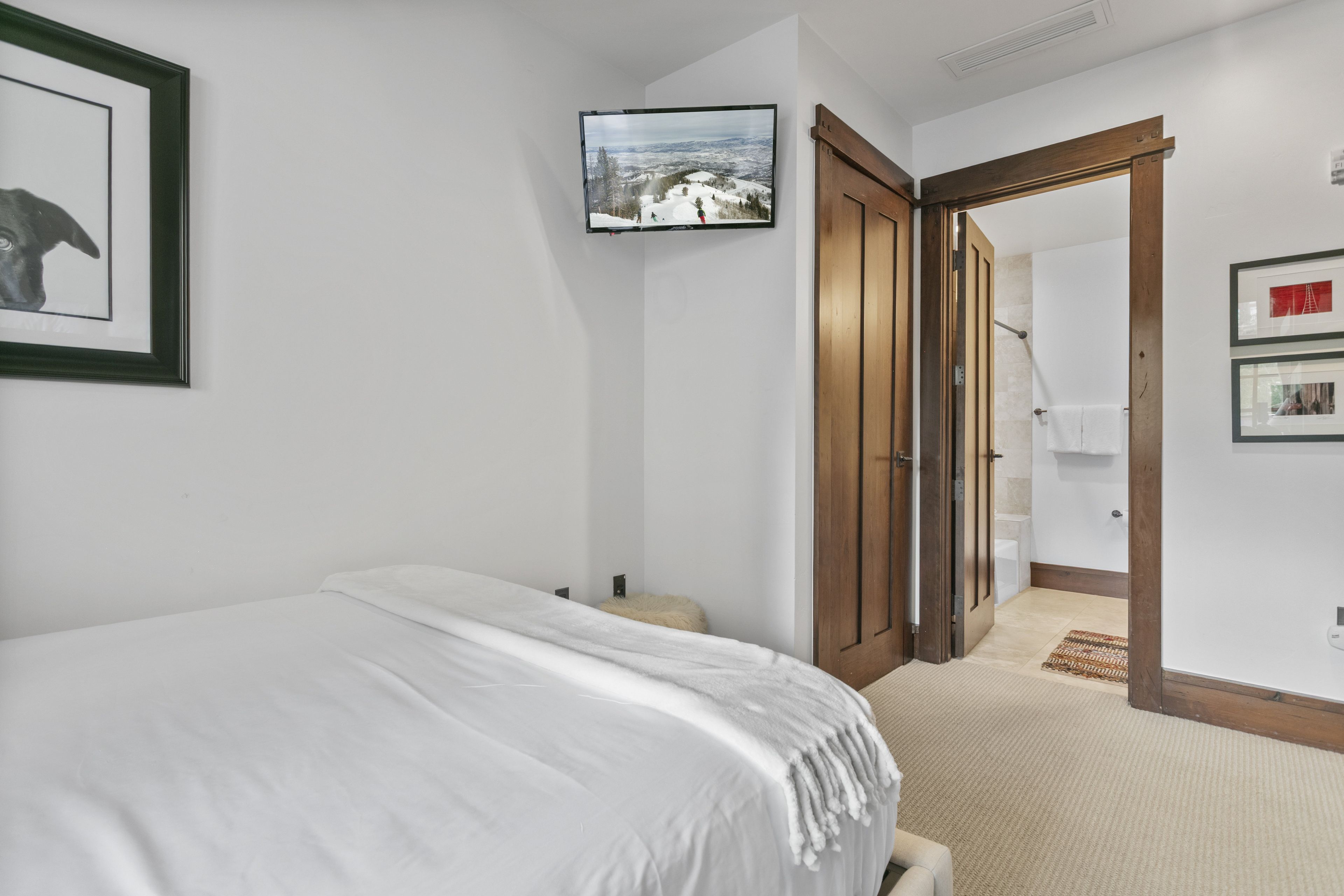 Un dormitorio con cama, una puerta que da a otra habitación y un cuadro en la pared.