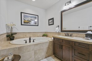 A bathroom with a large bathtub, a double sink vanity, and a mirror above the vanity. - 201 - Two Bedroom Arrowleaf 2 Condo (Park City)