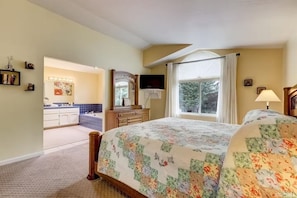 Un dormitorio con cama, cómoda, espejo, ventana con cortinas y baño con bañera.