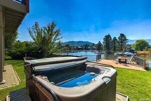 Un jacuzzi en una terraza con vista a un puerto deportivo y colinas al fondo.