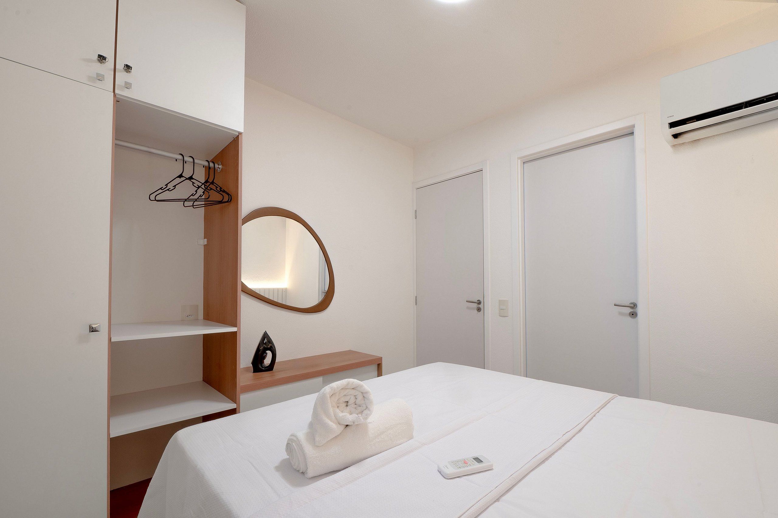 A hotel room with a bed, a bedside table, a mirror, a wardrobe, and a door.