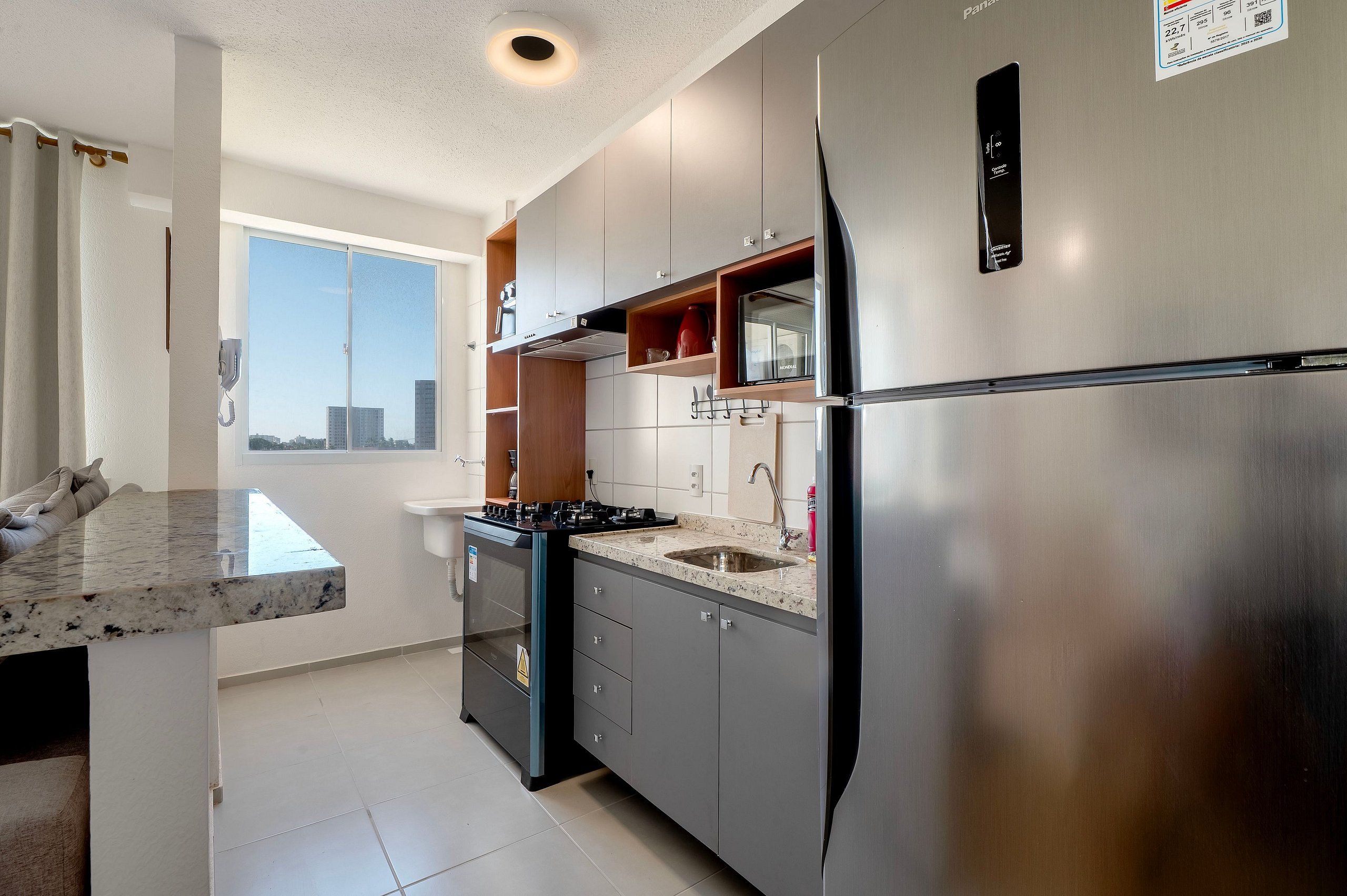 Una cocina moderna con un refrigerador de acero inoxidable, un horno empotrado y un ventanal con vistas a la ciudad.