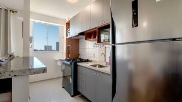 Una cocina moderna con un refrigerador de acero inoxidable, un horno empotrado y un ventanal con vistas a la ciudad.