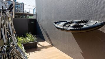 A boat mounted on a textured wall, a metal rack with pipes, and a small planter with plants.