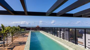 A rooftop pool with a clear view of the ocean and city skyline.