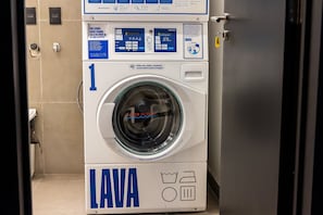 Vista frontal de uma máquina de lavar roupa branca e azul, com visor digital e painel de controle.