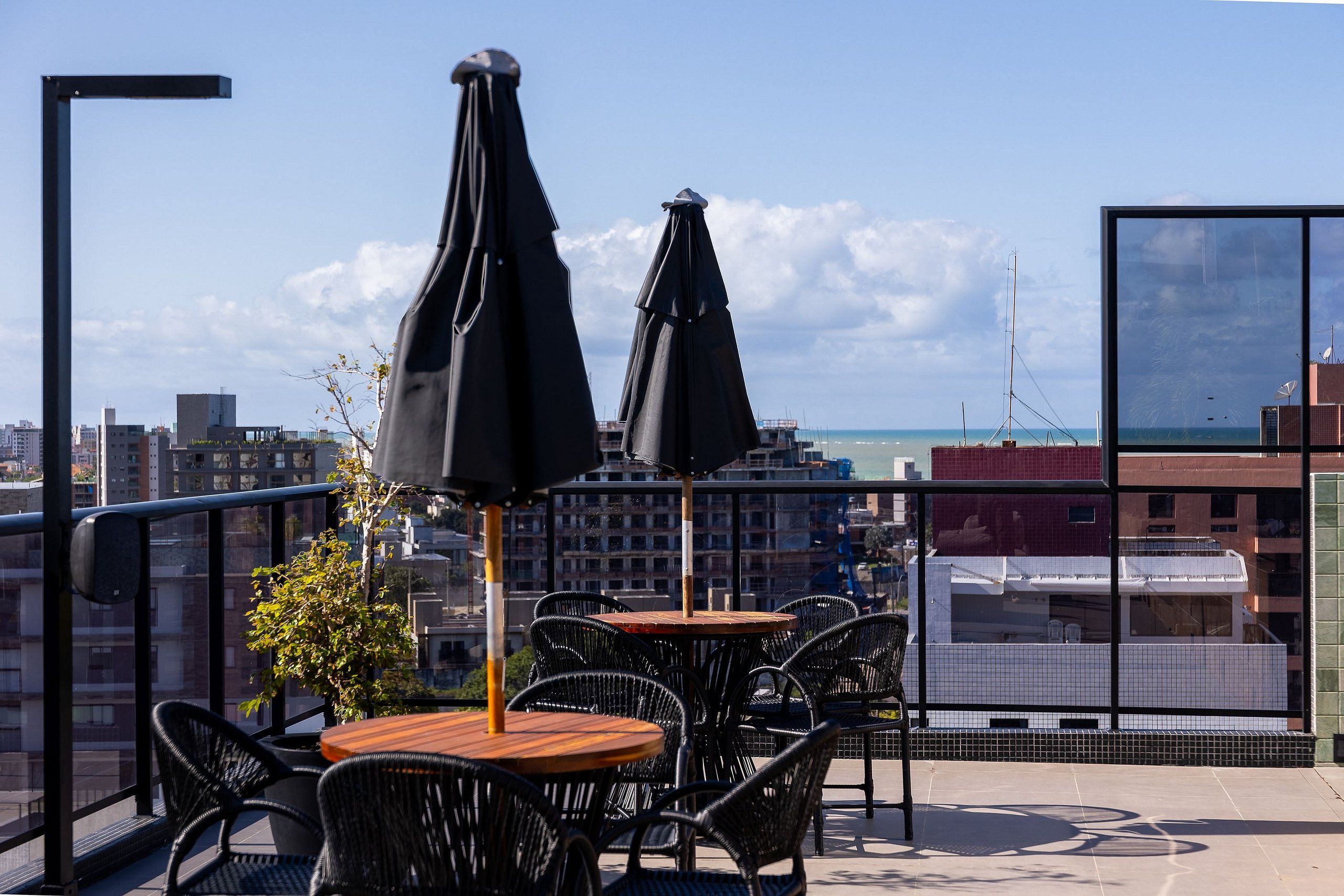 A balcony with outdoor seating, including tables and chairs, and two umbrellas.