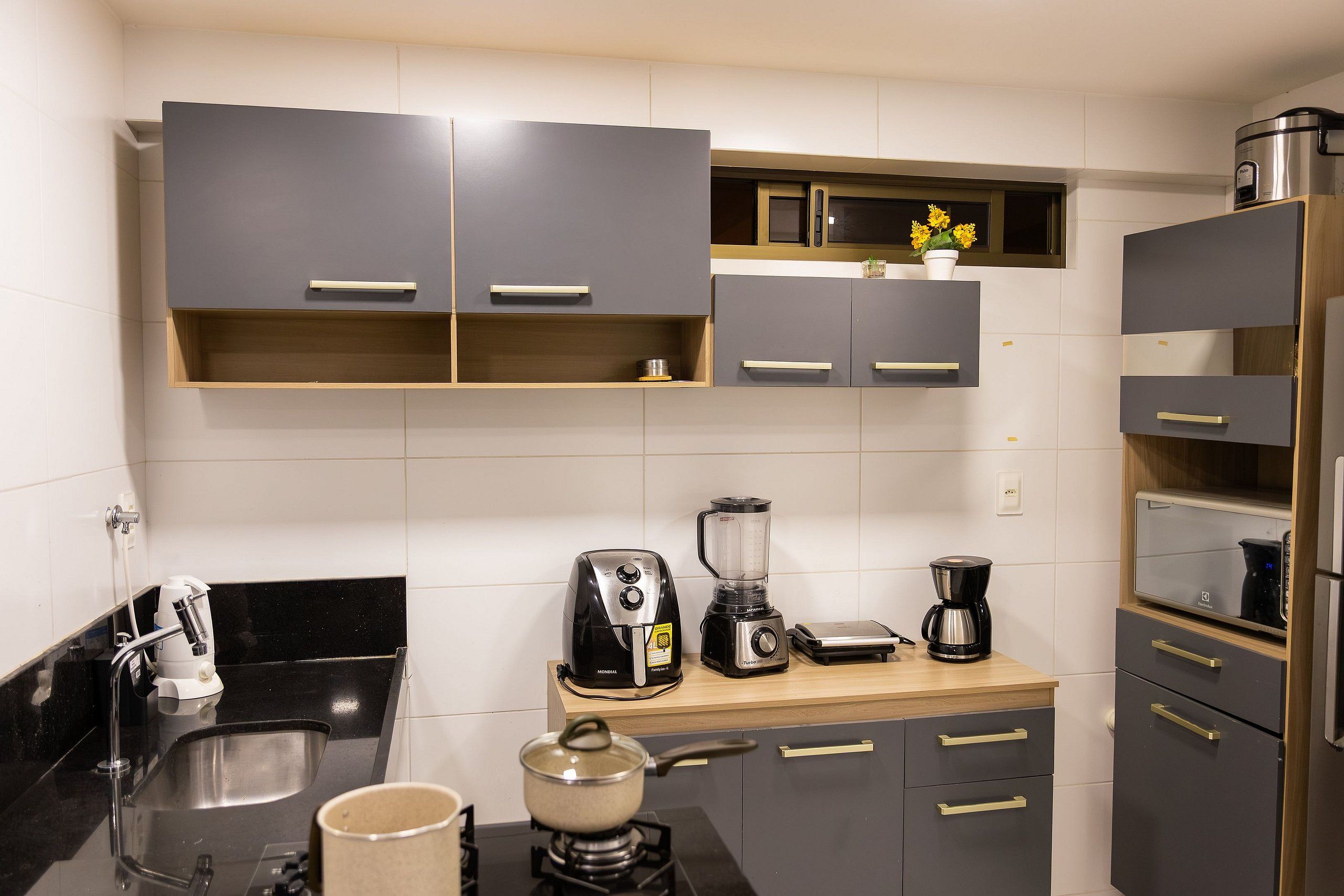 Una cucina moderna con mobili grigi, una macchina da caffè, un frullatore e un bollitore.