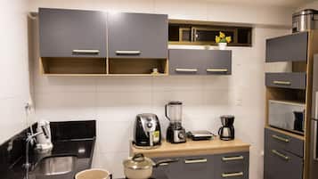 Una cucina moderna con mobili grigi, una macchina da caffè, un frullatore e un bollitore.