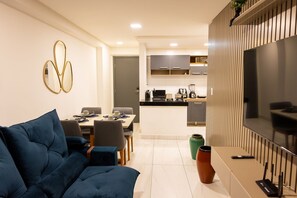 A modern living room with a sofa, dining table, and kitchen area with cabinets and appliances. - Mardisa Design #705 in Cabo Branco by Carpediem (João Pessoa)