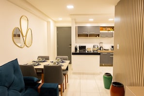 A modern kitchen with a dining area, a sofa, and a decorative mirror. - Mardisa Design #705 in Cabo Branco by Carpediem (João Pessoa)