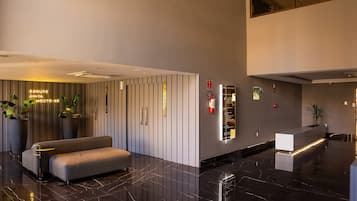 Una hall moderna con reception, area salotto e segnaletica direzionale.
