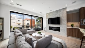 A modern living room with a sofa, a coffee table, and a TV mounted on the wall. - The Venice Modern in Venice (Venice)