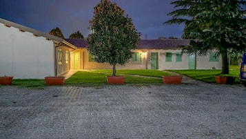 A courtyard with a paved ground, a tree, and a building with a tiled roof.