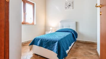 Una camera da letto con un letto, un comodino, una finestra e un quadro appeso al muro.
