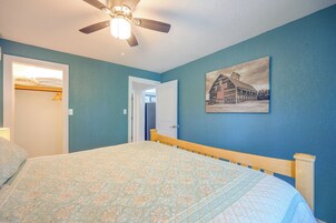 A bedroom with a bed, a ceiling fan, a door, and a wall-mounted picture.