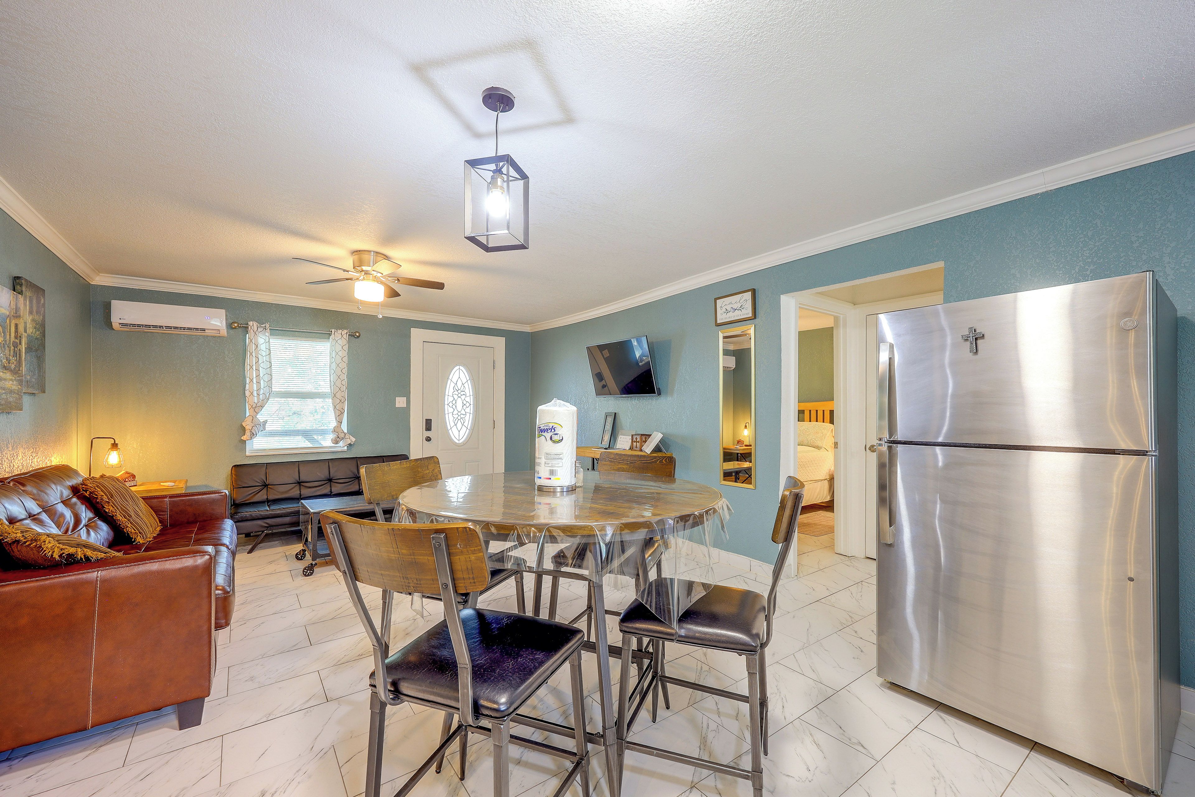 Una cocina compacta con refrigerador, mesa de comedor, sillas y ventilador de techo.