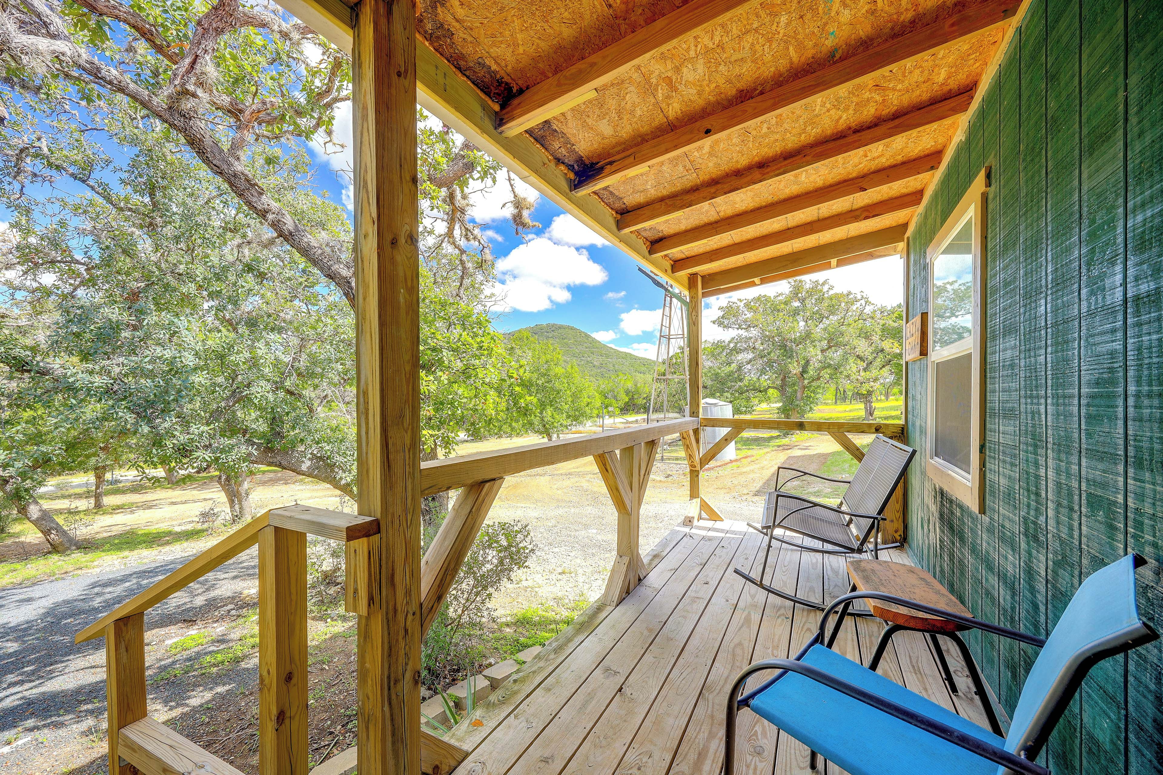Una terraza de madera con barandilla, un banco y una mesa.