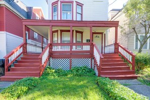 A two-story house with a porch, a front yard with a small garden, and a mailbox. - Walk to Rosamond Gifford Zoo & Dining! Cozy Unit (Syracuse)