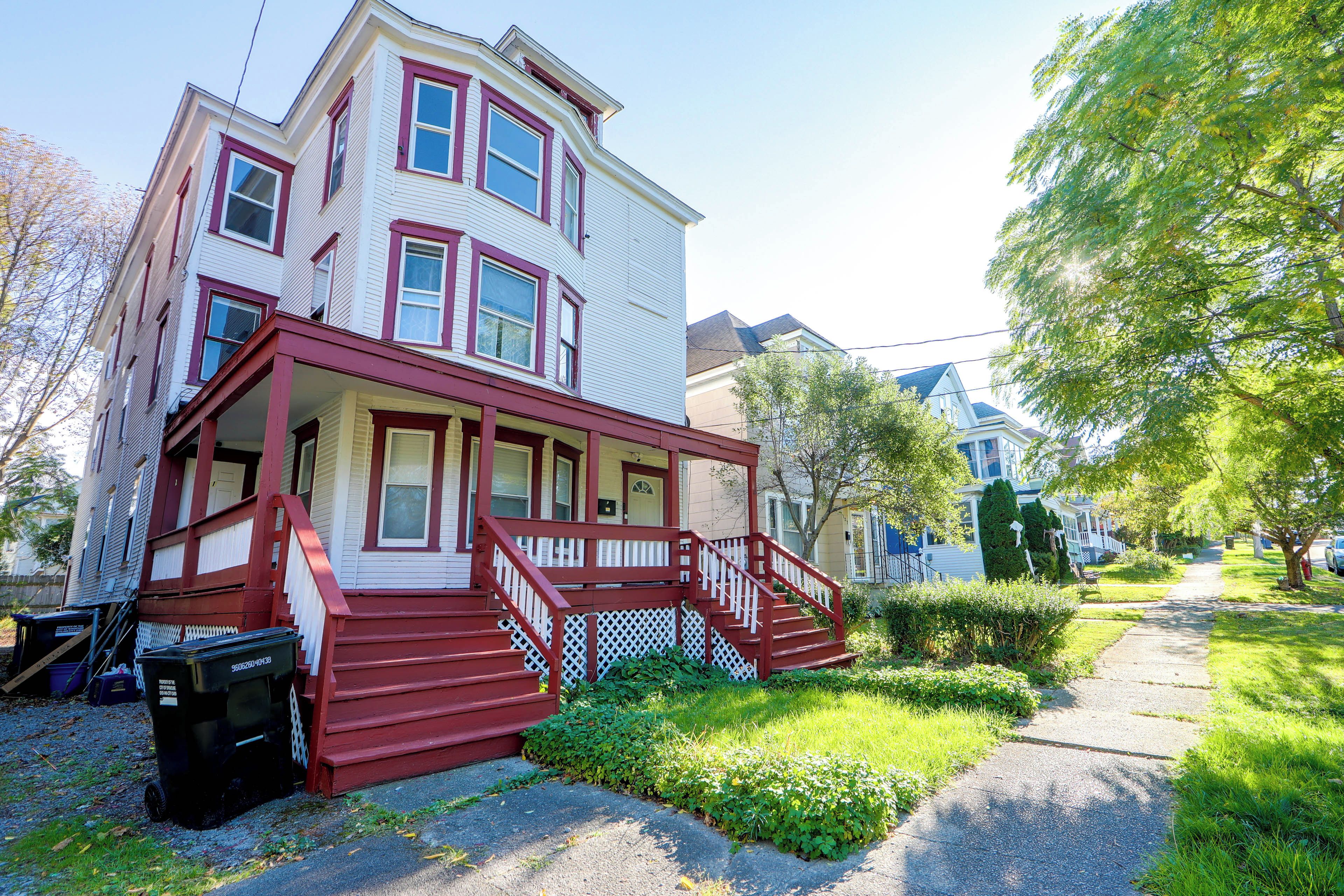 A two-story house with a porch and a staircase leading to the entrance.