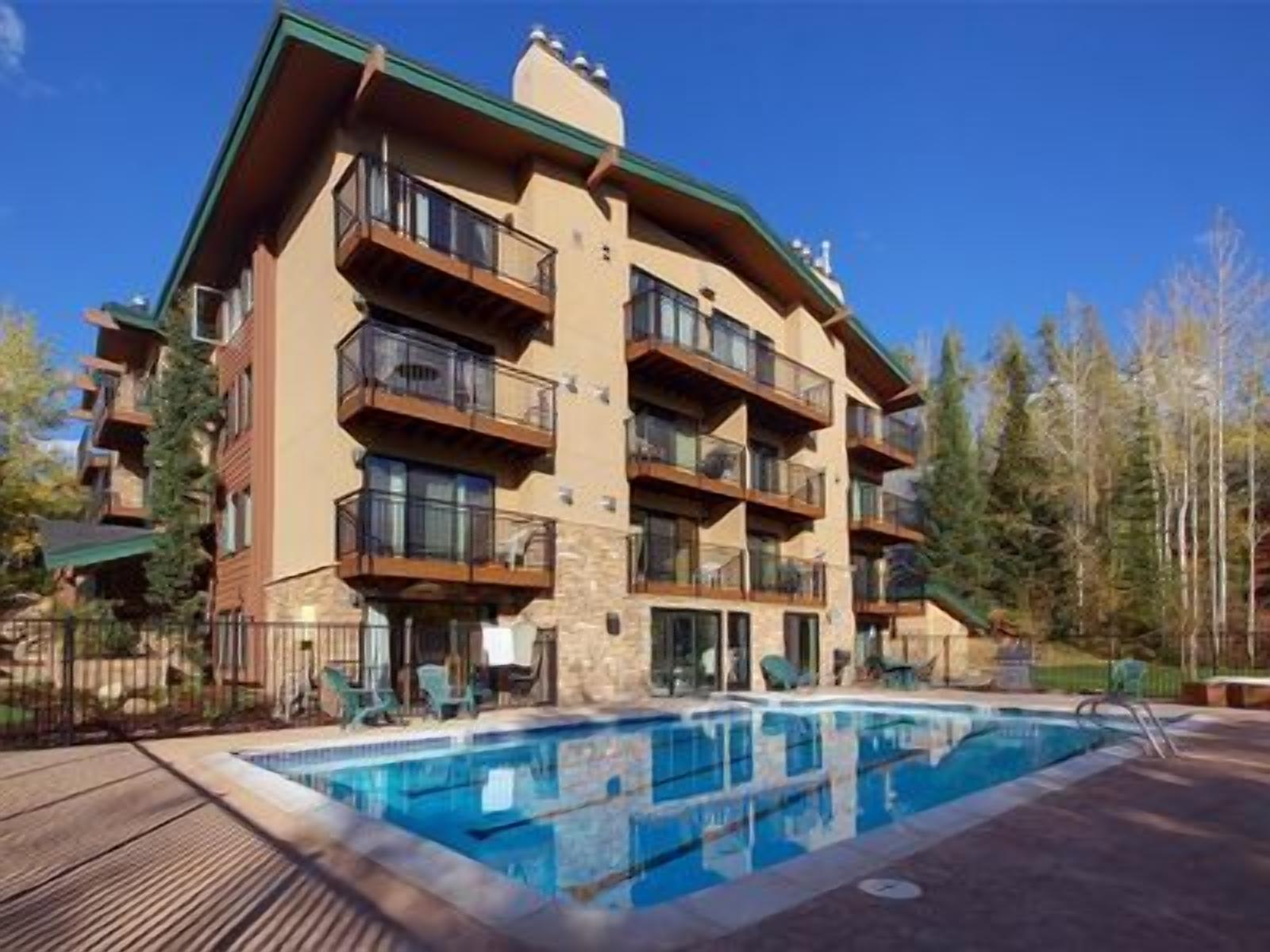 A multi-story building with a pool area, balconies, and a wooden deck.