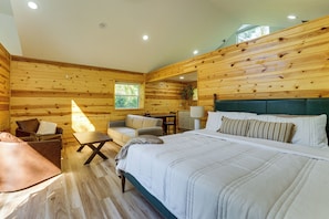 Ein holzgetäfelter Raum im Blockhausstil mit einem Bett, zwei Stühlen, einem Tisch und einem Fenster.