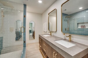 Un baño moderno con dos lavamanos, ducha y un espejo grande.