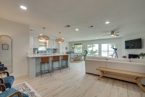 A modern kitchen with a central island, bar stools, and a dining area with a view. - Putt, Play & Splash! Cedar Creek Lake Getaway (Mabank)