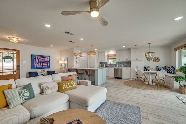 A modern living room with a sofa, coffee table, and a dining area with chairs and a table. - Putt, Play & Splash! Cedar Creek Lake Getaway (Mabank)