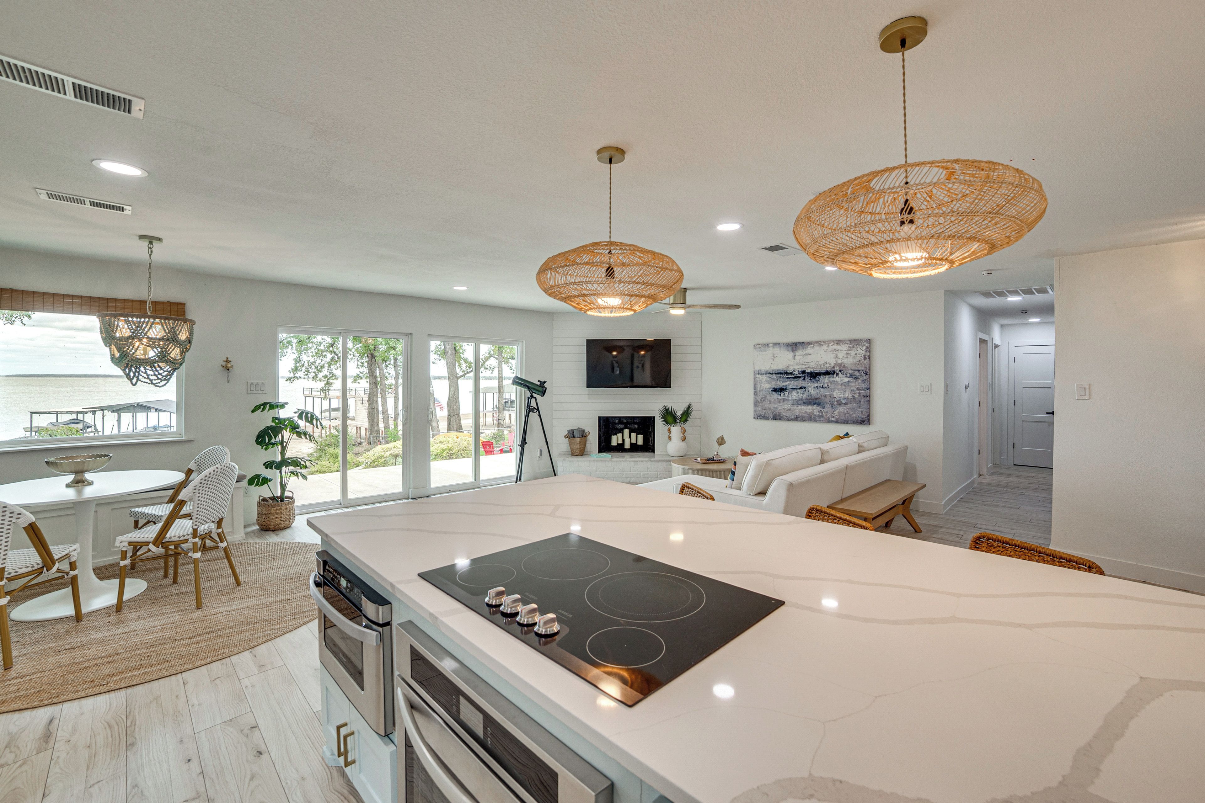 A modern kitchen with a large island, built-in oven, and a dining area with a table and chairs.