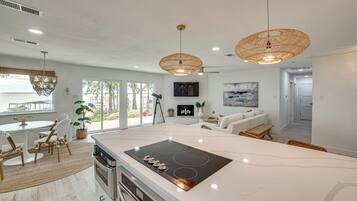 A modern kitchen with a large island, built-in oven, and a dining area with a table and chairs.
