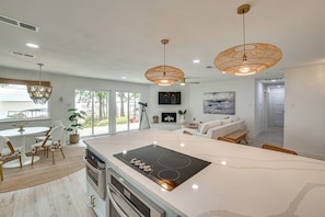 A modern kitchen with a large island, built-in oven, and a dining area with a table and chairs. - Putt, Play & Splash! Cedar Creek Lake Getaway (Mabank)
