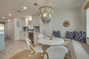 A modern kitchen with white cabinets, a dining area with a round table, and a seating area with patterned cushions. - Putt, Play & Splash! Cedar Creek Lake Getaway (Mabank)