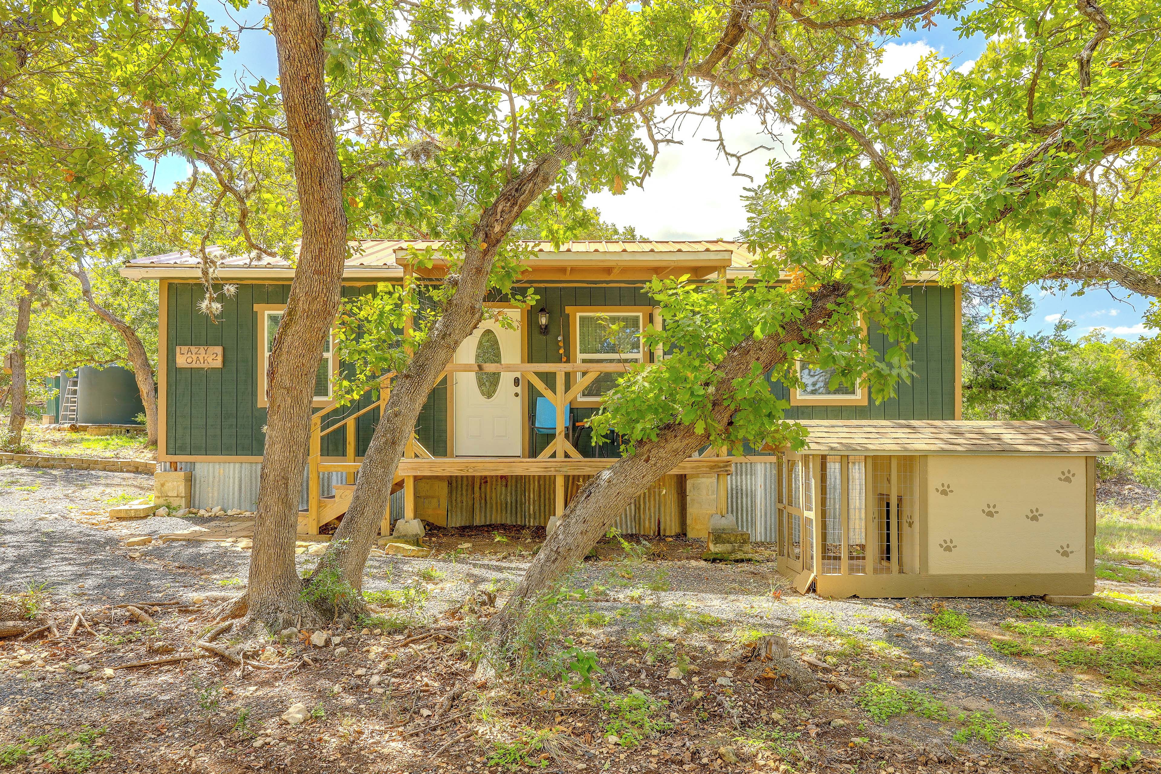 A rustic cabin with a porch, surrounded by trees.