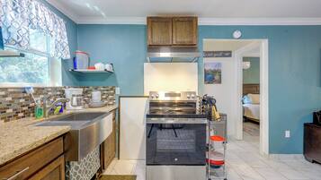 A modern kitchen with a stainless steel range, a built-in oven, and a window with patterned curtains.